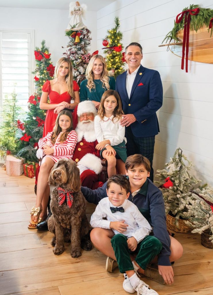 The Boggess family (including their beloved labradoodle, Nova) snuggles up with Santa in front of the Christmas trees in their Juno Beach home. Photo by Jerry Rabinowitz
